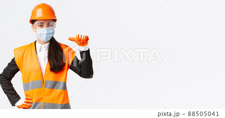 Covid-19 safety protocol at enterpise, construction and preventing virus concept. Confident asian female engineer in helmet and face mask pointing at herself, advertise personal assitance Covid-19 safety protocol at enterpise, construction and preventing virus concept. Confident asian female engineer in helmet and face mask pointing at herself, advertise personal assitance 88505041