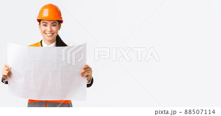 Excited smiling asian female engineer at construction area study blueprints, looking pleased while reading documents, building plan, standing in safety helmet over white background Excited smiling asian female engineer at construction area study blueprints, looking pleased while reading documents, building plan, standing in safety helmet over white background 88507114