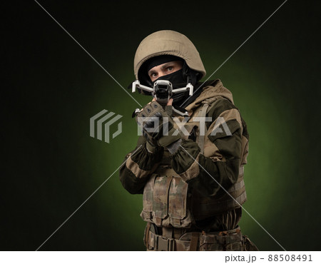 a soldier in military clothes with a weapon launches a small unmanned quadcopter for reconnaissance on a dark background a soldier in military clothes with a weapon launches a small unmanned quadcopter for reconnaissance on a dark background 88508491