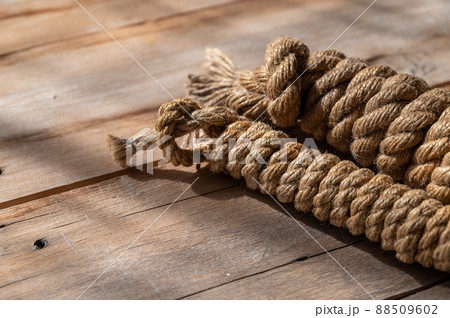 Coiling a natural rope against a wooden background. Rough, cracked boards. Natural lighting. 88509602
