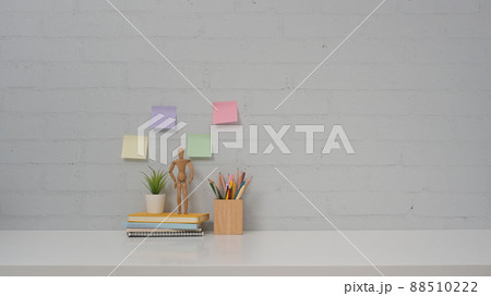 Personal accessories on white table and colorful sticky notes on brick wall background. Copy space for your advertise tex. Personal accessories on white table and colorful sticky notes on brick wall background. Copy space for your advertise tex. 88510222