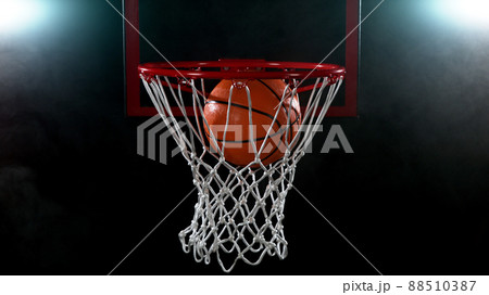 Basketball going through the basket on black backgorund 88510387