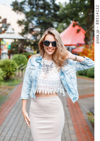 Elegant happy young hipster woman with beautiful smile in stylish clothes in sunglasses on a walk in an amusement park on a summer sunny day. Stylish positive girl on vacation. Great weekend. Elegant happy young hipster woman with beautiful smile in stylish clothes in sunglasses on a walk in an amusement park on a summer sunny day. Stylish positive girl on vacation. Great weekend. 88514132