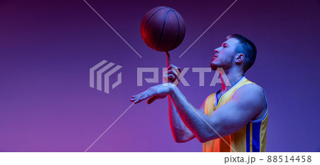 Spin. Studio shot of muscled man, basketball player training with ball isolated on purple background in neon light. Goals, sport, motion, activity concepts. 88514458
