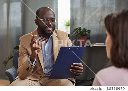 Skilled young African-American psychologist in eyeglasses gesturing hand while explaining reason of emotional problem to patient 88516970
