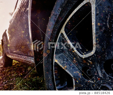 Concept image of the dirty front wheel of SUV and its side door splattered with mud, with sun spots 88518426