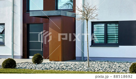 Entrance to a minimalist modern home with a rock garden containing a tree with bare branches 88518692