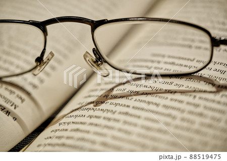 Close up of reading glasses lying on open book, selective focus 88519475