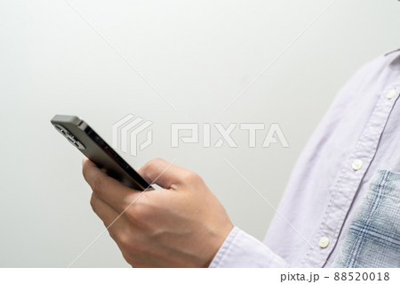 男性がスマホを操作している上半身のクローズアップ 88520018