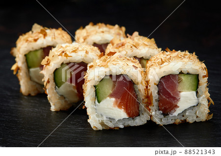 Traditional delicious fresh sushi roll set on a black background. Sushi roll with rice, cream cheese, avocado, salmon, sesame. Philadelphia. Sushi menu. Japanese kitchen, restaurant. 88521343