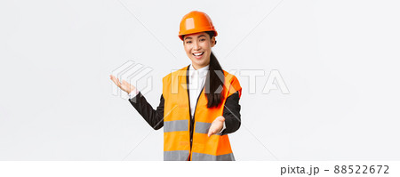 Smiling successful female asian construction manager, architect introduce her project, pointing hand at blueprint, explain her building plan. Industrial woman giving speech to investors Smiling successful female asian construction manager, architect introduce her project, pointing hand at blueprint, explain her building plan. Industrial woman giving speech to investors 88522672