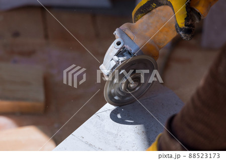 The worker cuts the tiles with a special tool with a diamond disc 88523173