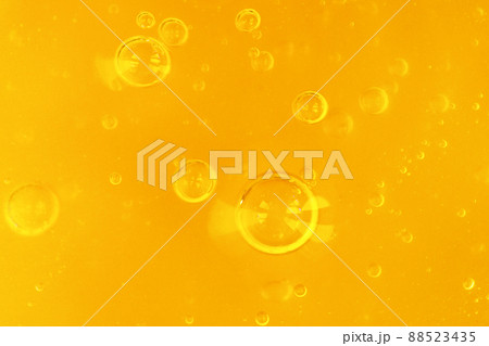 Texture of transparent yellow gel with air bubbles and waves on orange background. Concept of skin moisturizing, body care and prevention of covid19. Liquid beauty product closeup. Backdrop, flat lay 88523435