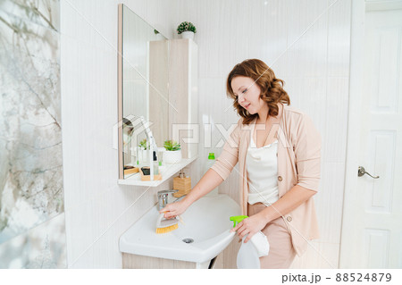 an attractive housewife washes the sink in bathroom an attractive housewife washes the sink in bathroom 88524879