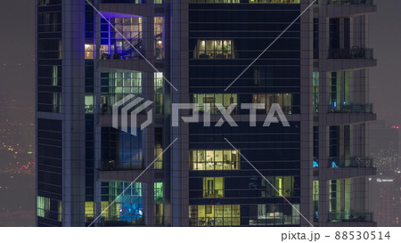 Windows in high-rise building exterior in the late evening with interior lights on timelapse 88530514