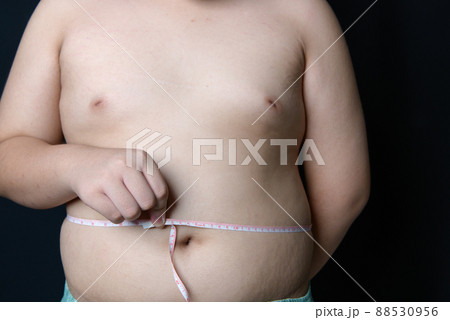 obese fat boy measuring tape of stomach isolated on black  background, healthy and lose weight 88530956