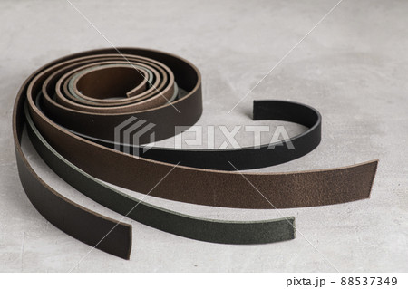 Leather belt blanks are rolled up in a circle on a gray background. View from above. copy space 88537349