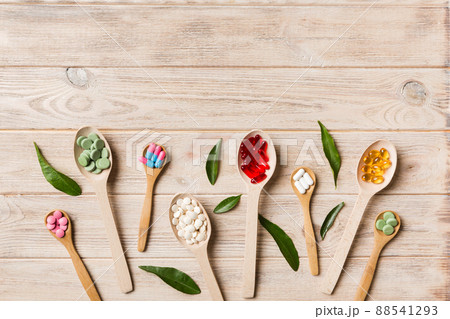 Top view Variety of vitamin and mineral pills in wooden spoon on Colored background. Top view of assorted pharmaceutical medicine pills. Dietary supplement healthcare product 88541293