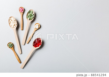 Top view Variety of vitamin and mineral pills in wooden spoon on Colored background. Top view of assorted pharmaceutical medicine pills. Dietary supplement healthcare product Top view Variety of vitamin and mineral pills in wooden spoon on Colored background. Top view of assorted pharmaceutical medicine pills. Dietary supplement healthcare product 88541294