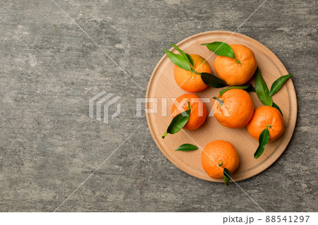 Fresh cutted clementines and whole mandarin over round plate on colored background. Food and drink ingredients preparing. healthy eating theme top view vith copy space 88541297
