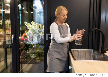 flower shop worker washes vases in the sink and fills them with water for flowers, florist Concept flower shop worker washes vases in the sink and fills them with water for flowers, florist Concept 88543846