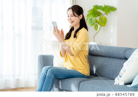 部屋でスマホを操作する若い女性 部屋でスマホを操作する若い女性 88545789