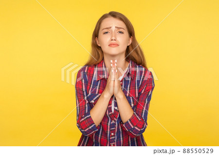 Please, I'm begging. Portrait of desperate ginger girl in shirt keeping arms in prayer gesture and asking forgiveness, feeling sorry for mistake. indoor studio shot isolated on yellow background Please, I'm begging. Portrait of desperate ginger girl in shirt keeping arms in prayer gesture and asking forgiveness, feeling sorry for mistake. indoor studio shot isolated on yellow background 88550529