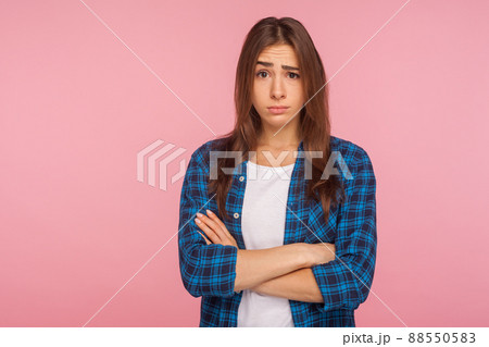Portrait of displeased unhappy brunette girl in bad mood looking at camera with resentful vexed face and holding hands crossed, worried about failure. indoor studio shot isolated on pink background 88550583