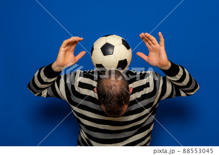 Hispanic man with incipient baldness trying to juggle a soccer ball, he has the ball on the back of his neck while raising his arms. Isolated on blue studio background Hispanic man with incipient baldness trying to juggle a soccer ball, he has the ball on the back of his neck while raising his arms. Isolated on blue studio background 88553045