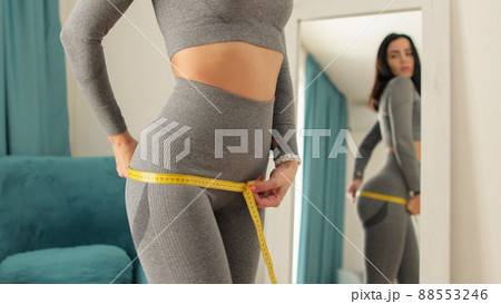 slim Woman waist Measuring With Tape at home 88553246