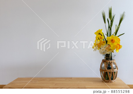 花瓶に生けて室内の白い壁際に置いた水仙の花と麦の穂 88555298