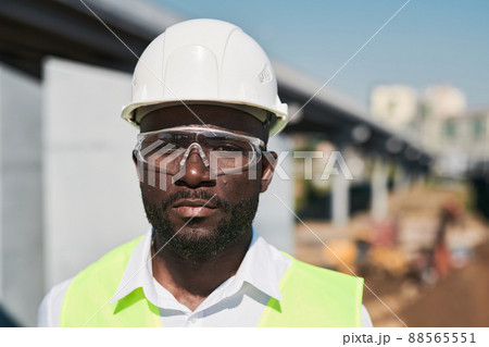 Serious handsome mixed race construction foreman in glasses standing at construction site 88565551