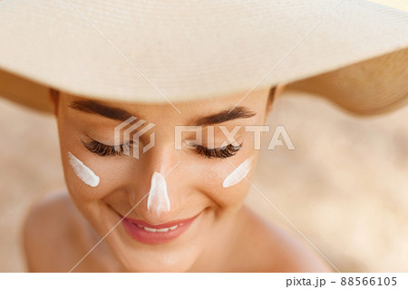 Woman smile applying sun cream on face. Skin care. Body Sun protection. Sunscreen. Woman smile applying sun cream on face. Skin care. Body Sun protection. Sunscreen. 88566105
