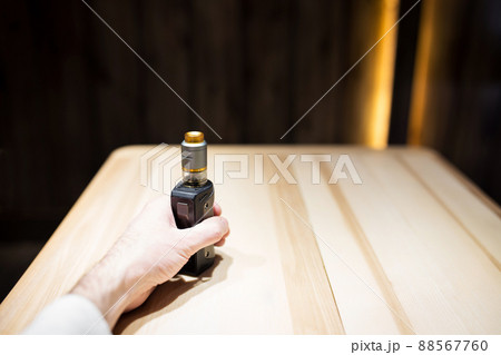 A man's hand holds vape in a cafe, safe smoking 88567760