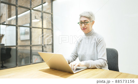 Mature asian business woman wears glasses using laptop computer sit at workplace desk Mature asian business woman wears glasses using laptop computer sit at workplace desk 88573156