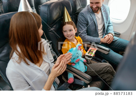 Happy parents celebrating kid birthday in airplane Happy parents celebrating kid birthday in airplane 88573183