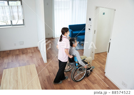 車椅子に乗った男性をサポートする女性 88574522
