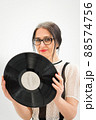 Studio photo of middle aged woman starting getting grey-haired wearing black and white clothes with vinyl record in hands on white background, middle age sexy lady, happy life concept 88574756