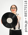 Studio photo of middle aged woman starting getting grey-haired wearing black and white clothes with vinyl record in hands on white background, middle age sexy lady, happy life concept 88575518