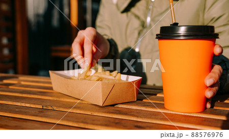 Woman eating tasty french fries and drinking tea in outdoor cafe. Close-up photo 88576976
