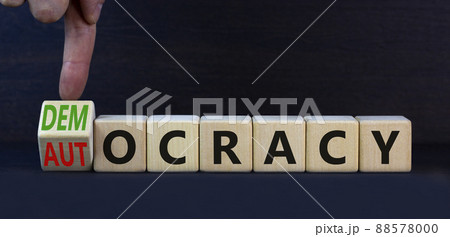 Democracy or autocracy symbol. Turned wooden cubes and changed the concept word Autocracy to Democracy. Beautiful grey background. Copy space. Business democracy or autocracy concept. 88578000