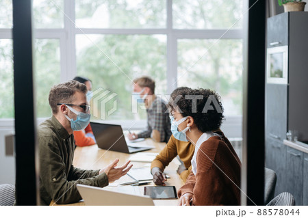 employees in protective masks work in the hall of the coworking 88578044