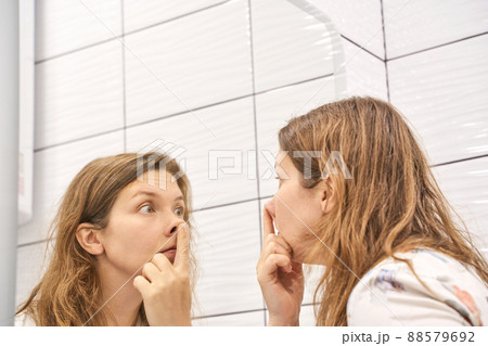 Mirror reflection nose touch. Young woman doing morning hygiene. portrait indoor Mirror reflection nose touch. Young woman doing morning hygiene. portrait indoor 88579692