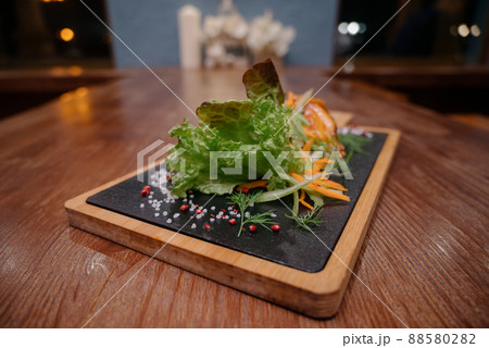 A juicy piece of fried meat lies on a cutting board against a wooden table. A juicy piece of fried meat lies on a cutting board against a wooden table. 88580282