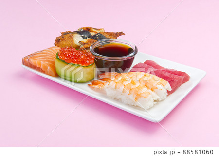 traditional japanese sushi set on a white plate isolated on a pink background. tasty set of sushi, nigiri, sahimi and maki. delicious dinner or lunch for one person. traditional japanese sushi set on a white plate isolated on a pink background. tasty set of sushi, nigiri, sahimi and maki. delicious dinner or lunch for one person. 88581060