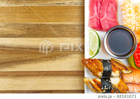 traditional japanese sushi set on a white plate with wood background. tasty set of sushi, nigiri, sahimi and maki. delicious dinner or lunch for one person. flat lay traditional japanese sushi set on a white plate with wood background. tasty set of sushi, nigiri, sahimi and maki. delicious dinner or lunch for one person. flat lay 88581071