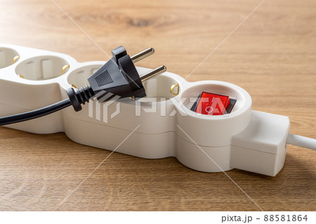 Unplugged electric appliance plug over switched off white power strip on the floor. Unplugged electric appliance plug over switched off white power strip on the floor. 88581864