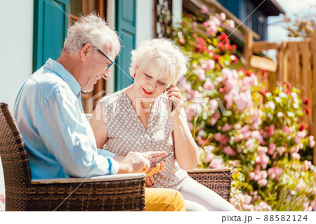 Senior couple looking at their phone in the garden Senior couple looking at their phone in the garden 88582124