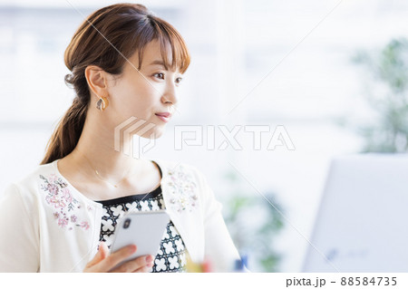 ノートパソコンを開いてスマホを操作する女性 ノートパソコンを開いてスマホを操作する女性 88584735