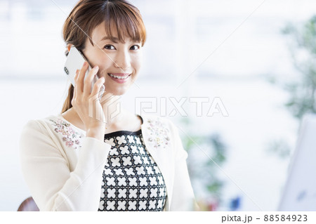 ノートパソコンを開いてスマホで通話する女性 ノートパソコンを開いてスマホで通話する女性 88584923